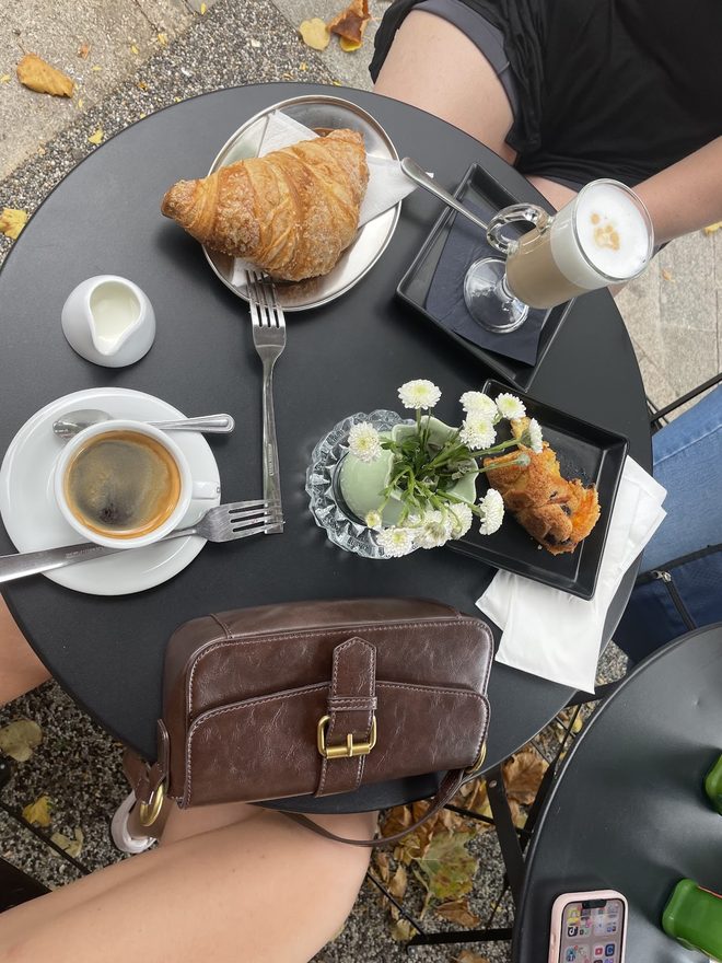 An overhead view of a pavement table with coffee and a croissant