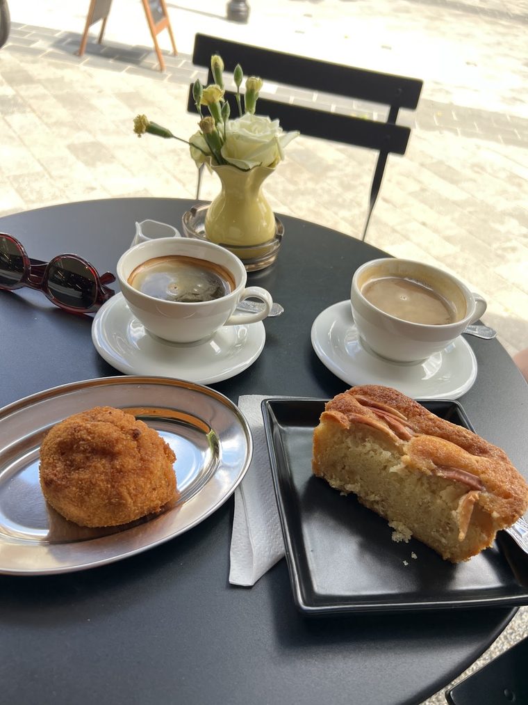 A cappuccino in a white cup beside a bombolone